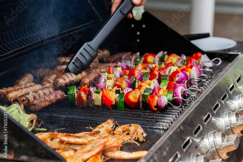 Kebabs, sausages, prawns and corn cooking together on bbq for lunch