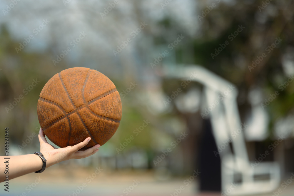 Hand holding a ball on an outdoor court. People, sport and active lifestyle concept Hand holding a ball on an outdoor court. People, sport and active lifestyle concept