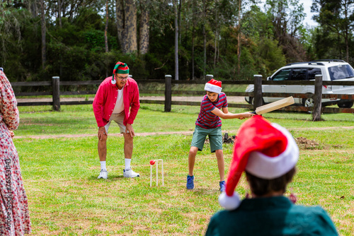 Christmastime backyard cricket game with ball about to get kid out photo