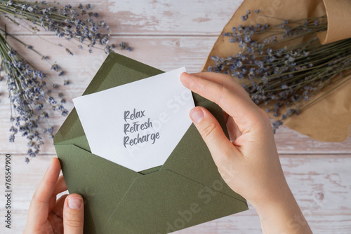 RELAX REFRESH RECHARGE text on supportive message paper note reminder from green envelope. Flat lay composition dry lavender flowers. Concept of inner happiness, slowing-down digital detox personal photo