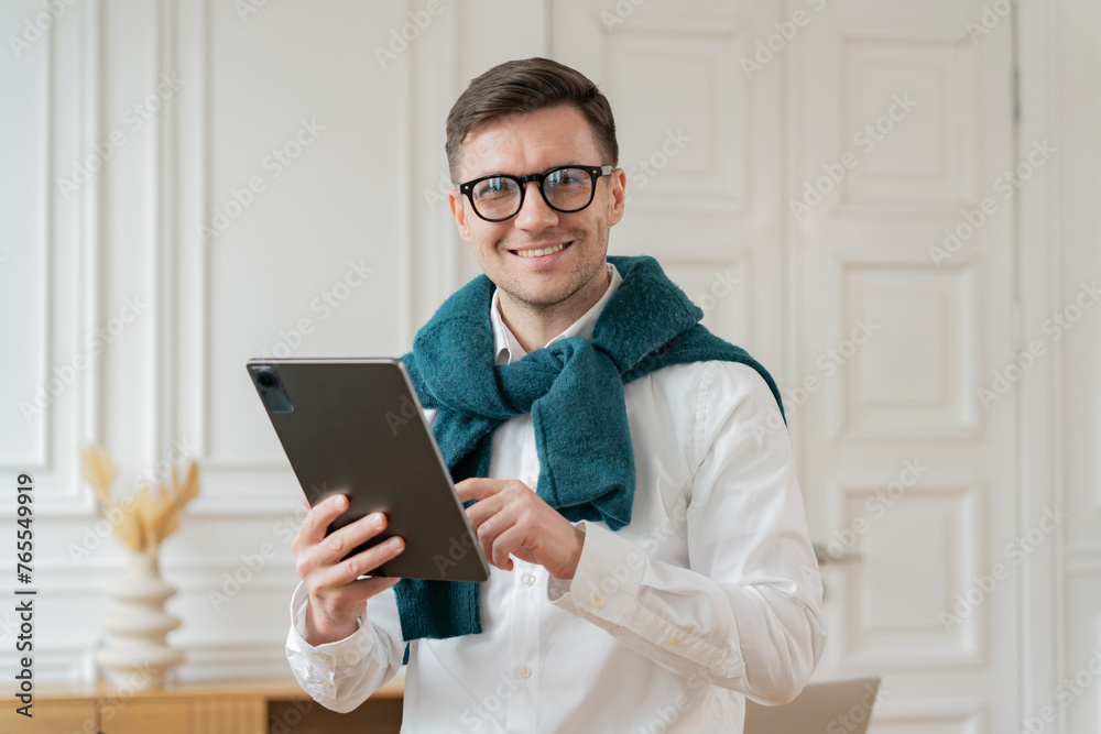 Professional in a scarf with a tablet smiles warmly in an elegant white office.
