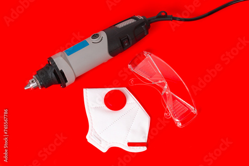 Wired Mini Drill, Safety Glasses and Dust Mask Isolated on Red