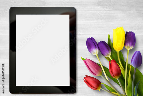 Fototapeta Naklejka Na Ścianę i Meble -  Tablet and colorful tulip flower on white wood table background.