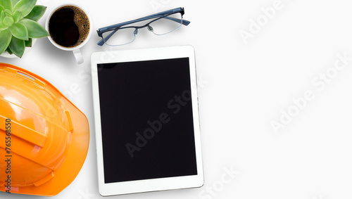 Office desktop with safety helmet and business tablet on white background with copyspace.
