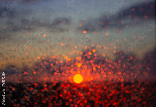 Sunset. Natural, defocus background. Abstract background. Raindrops on the glass. Defocus lights. Bokeh. The sun's glare. Raindrops.