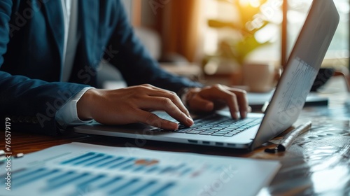 Obraz na płótnie Professional at Work on Laptop, Close-up of a businessman's hands typing on a laptop, with graphs on the screen, symbolizing focused data analysis and corporate work w salonie