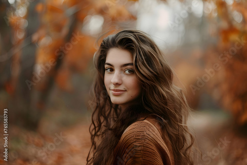 Woman walking through an autumn forest, smiling as she looks over her shoulder at the camera. The fall colors are bright and lively. Smiling depression concept.  photo