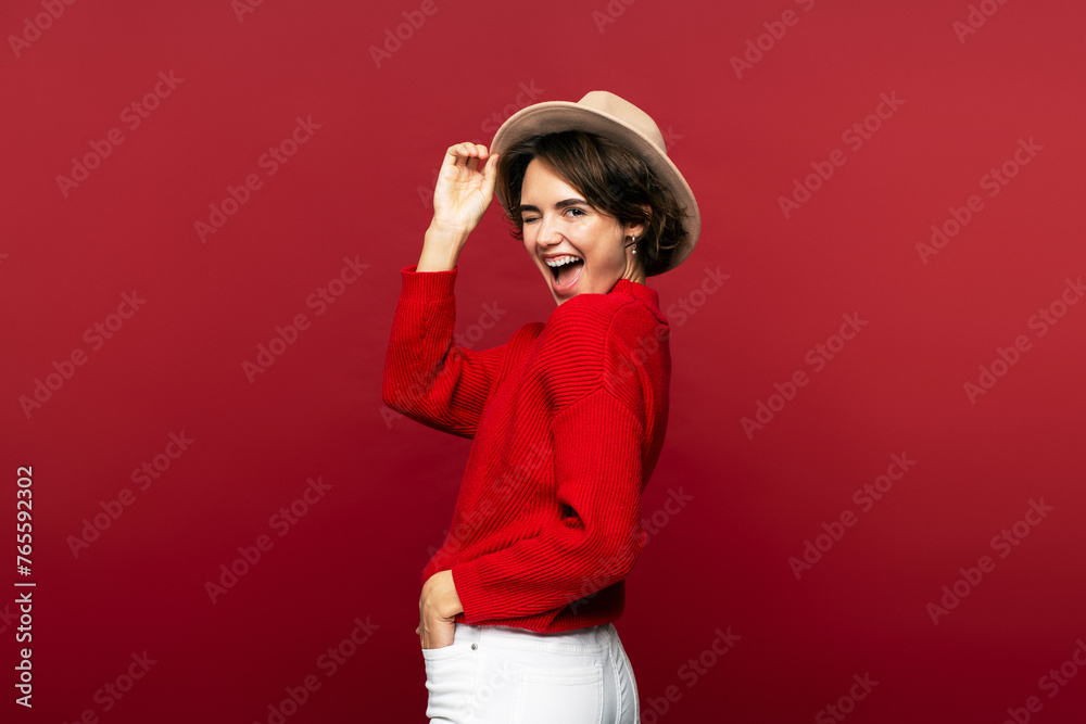 Woman, wearing stylish casual clothing and headwear, turning around and winking, looking into camera Woman, wearing stylish casual clothing and headwear, turning around and winking, looking into camera