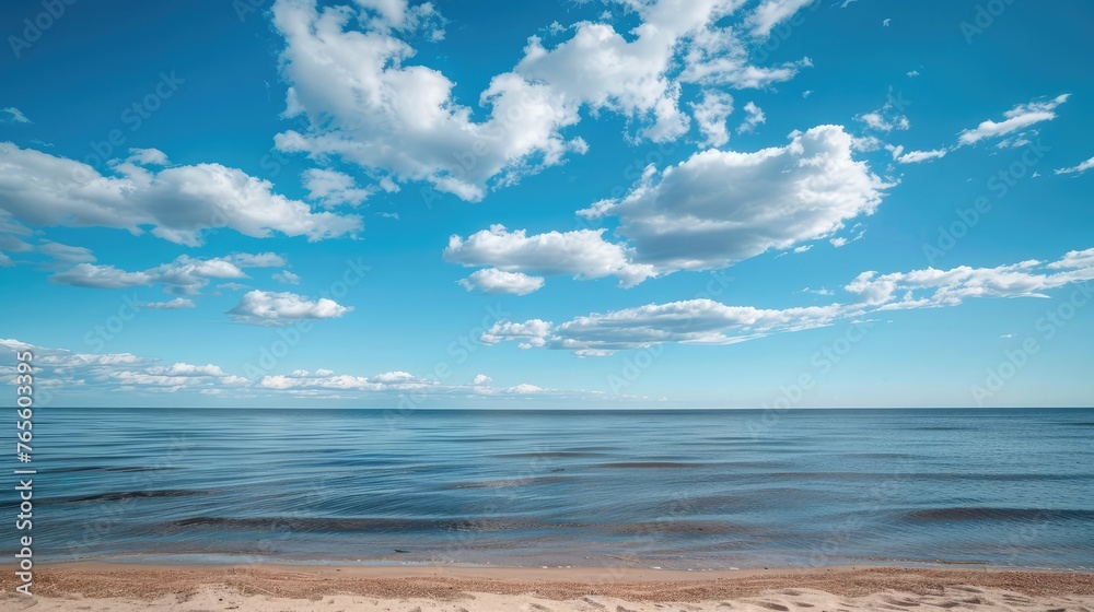 calm blue baltic sea against a blue sky with white cirrus clouds and an empty sandy beach