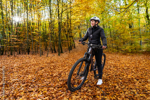 Woman riding bicycle in city forest in autumn scenery 