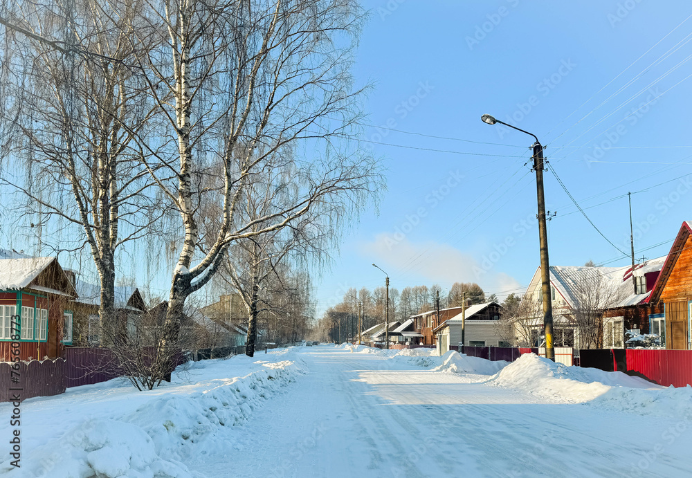 Winter village landscape. Sunny cold frosty day, Russian country street with snowdrifts and wooden houses.