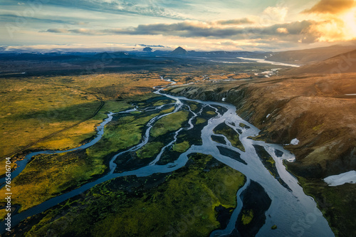 Dramatic sunset shines over volcanic mountain with glacier river flowing in Icelandic Highlands