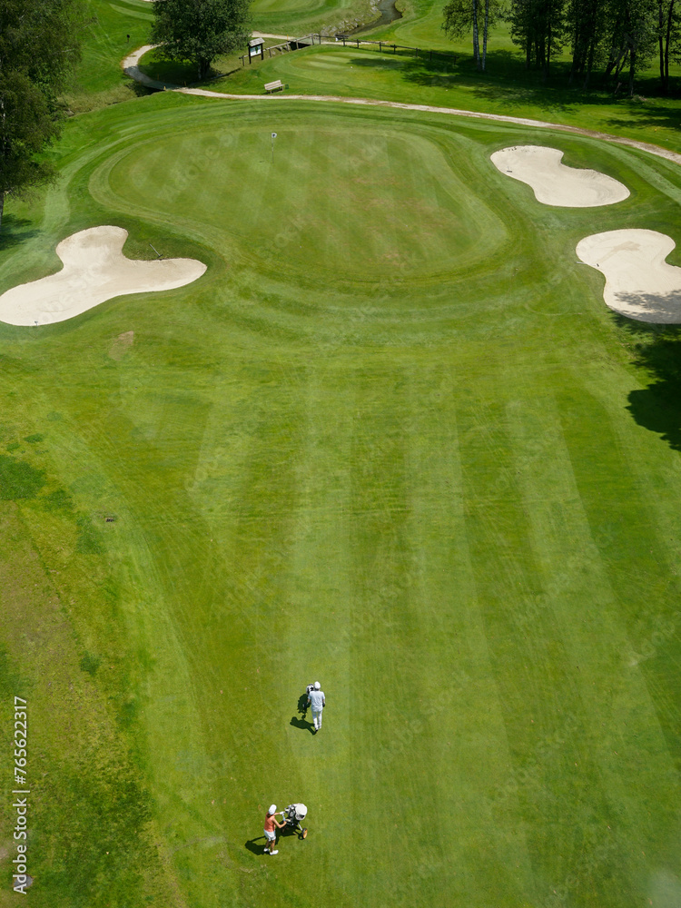 Luxurious beautiful golf course with well prepared green, fairway and bunkers and couple of golfers, aerial panoramic view, Chamonix, France