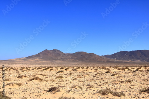 Gravel, dusty road with high volcanic mountains in the background. Jandia, Morro Jable, Fuerteventura, Canary Islands, Spain