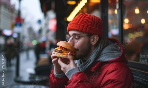 Man eating favorite cheeseburger near fast food outside. eating burger detail