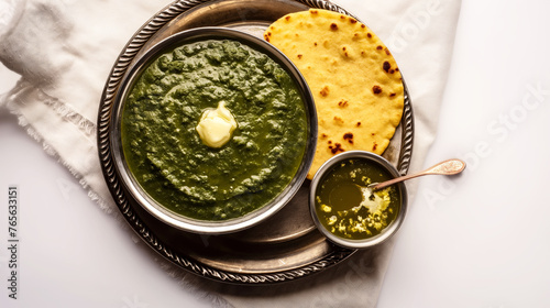 Makki ki Roti Sarson ka Saag, a famous Punjabi dish served on a metal plate, accompanied by clarified butter, top view on a white background. photo