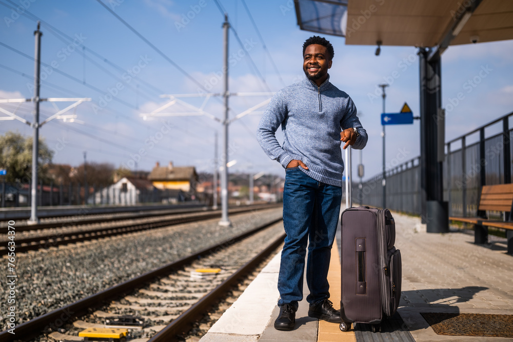 Happy man with suitcase standing on railway station. Happy man with suitcase standing on railway station.