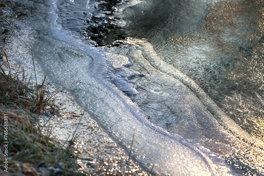 Zimowy widok na zamarzniętą wodę z kawałkami lodu.  - obrazy, fototapety, plakaty 