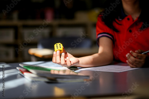 girl student at her desk working on maths problems using dice photo