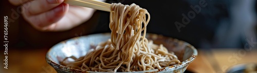 Action shot of soba noodles being lifted from a bowl with chopsticks emphasizing the texture and heartiness of the dish photo