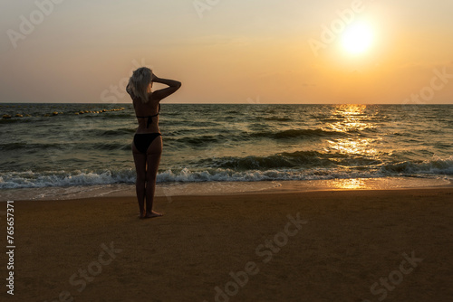  Caucasian woman in bikini swimsuit standing on the beach and enjoying sunset. people  summer vacation and leisure concept