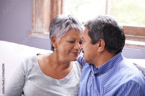 Love, sofa and elderly couple in living room with smile for love, care and embrace at home. Retirement, relax and senior people with happiness for romantic bonding, satisfaction and support in house