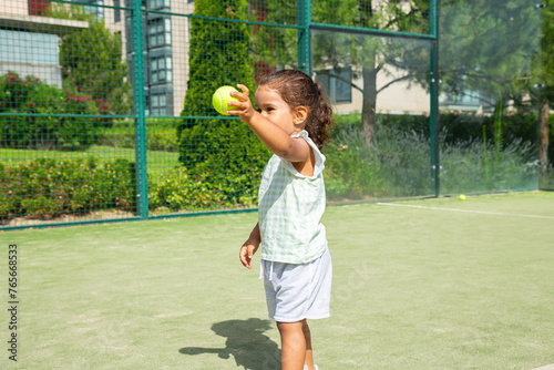 Little girl handing tennis ball on a padel tennis court