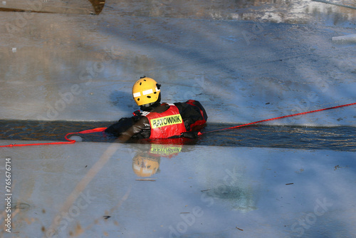 Ratownik wodny w zimie na lodzie ratuje topielca. 