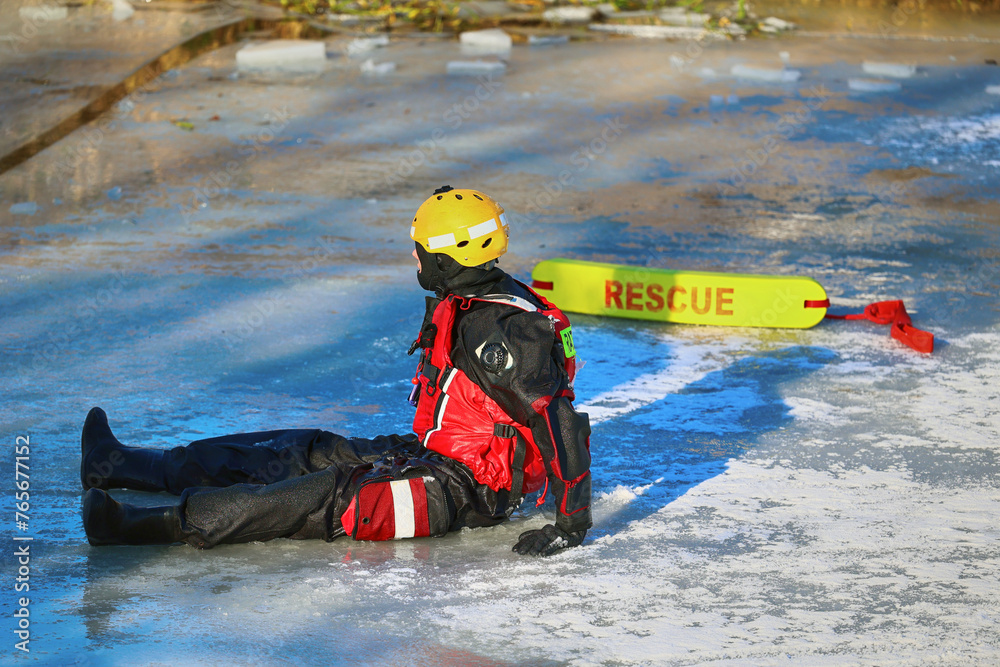 Ratownik wodny w zimie na lodzie ratuje topielca.  - obrazy, fototapety, plakaty 