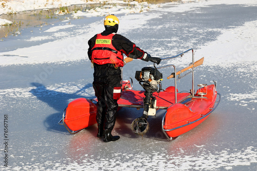 Ratownik wodny w zimie na lodzie ratuje topielca.  photo