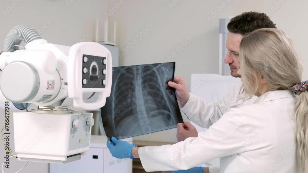 A young female doctor is talking with a senior colleague about x-rays in the office. Medical specialists consult on the final result. The concept of modern medical technologies and medicine. A young female doctor is talking with a senior colleague about x-rays in the office. Medical specialists consult on the final result. The concept of modern medical technologies and medicine.