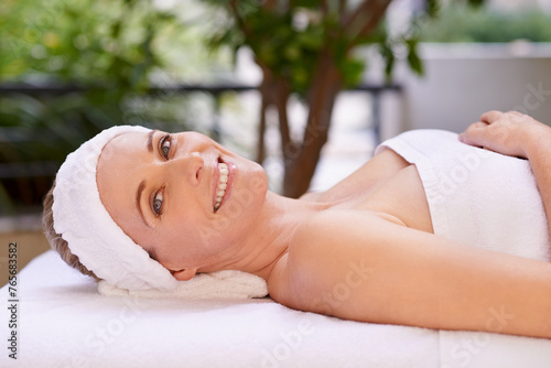 Happy woman  portrait and relax with towel for spa  zen or massage table at hotel or outdoor resort. Face of female person with smile  enjoying facial or body treatment at accommodation for wellness