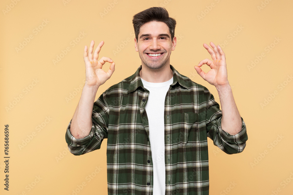 Naklejka premium Confident man making an okay gesture, posing against an isolated yellow background