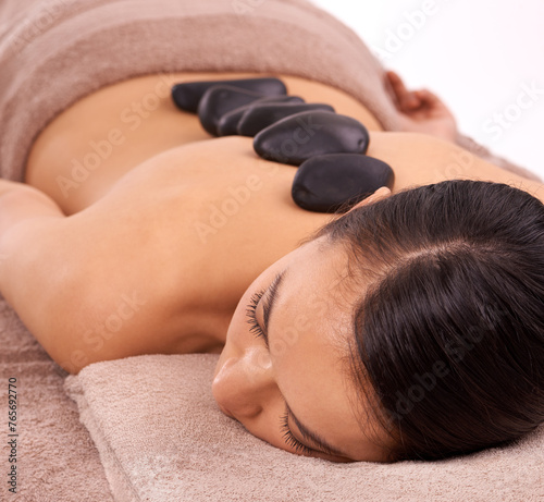 Wellness, hot stone and woman with back massage at spa for health, self care and grooming treatment in studio. Skin, calm and person with masseuse for warm rock body routine by white background.