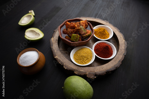 Homemade Mango Pickle or aam ka achar Kairi Loncha stored or preserved in China clay pot with Ingredients.