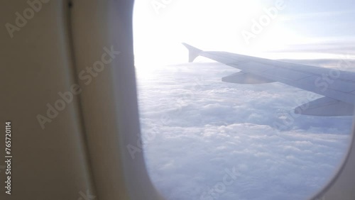view through the window of the airplane from inside cabin while flyiing climbing into the sky above the cloudscape outside in sunset time photo