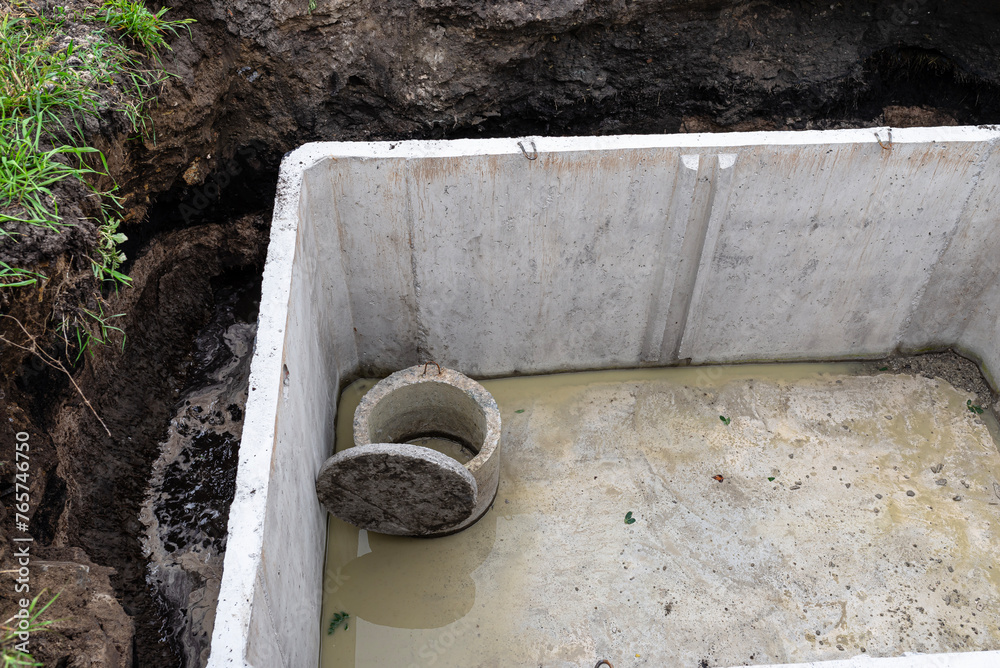 Concrete septic tank with a capacity of 10 m3 located in the garden next to the house, without a cover.