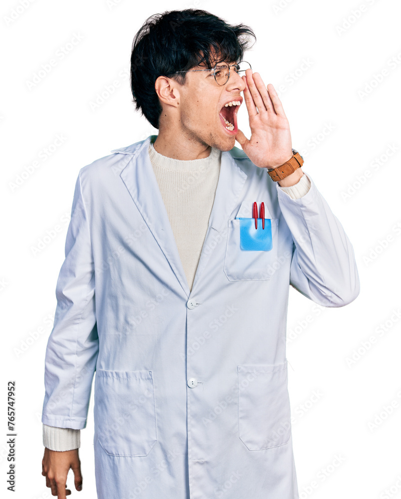 Handsome hipster young man wearing doctor uniform shouting and screaming loud to side with hand on mouth. communication concept. Handsome hipster young man wearing doctor uniform shouting and screaming loud to side with hand on mouth. communication concept.
