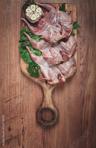 Raw quail meat, on a cutting board, with spices and herbs, top view, photo