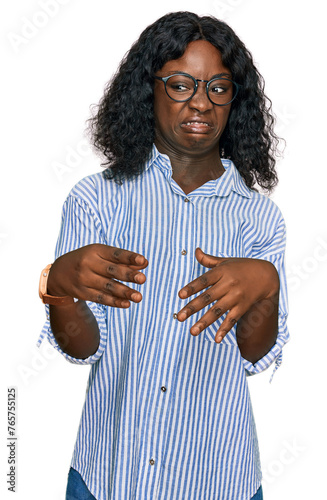 Beautiful african young woman wearing casual clothes and glasses disgusted expression, displeased and fearful doing disgust face because aversion reaction.