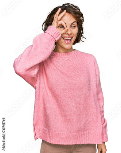 Young hispanic woman wearing casual clothes doing ok gesture with hand smiling, eye looking through fingers with happy face.