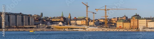 The sluice construction area between the old town Gamla Stan and he district Södermalm, yellow bridge and cranes, a sunny winter day in Stockholm