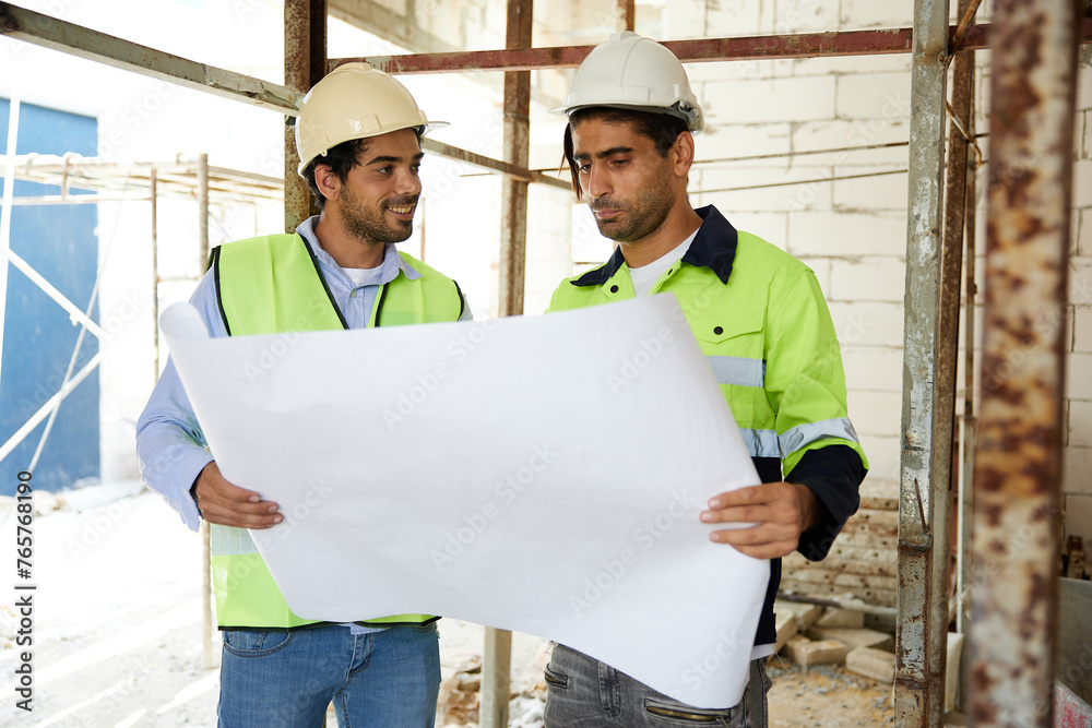 workers or architects holding and reading plan blueprint paper at construction site