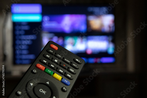 A TV remote control in close-up against the background of a working TV. Watching TV, switching channels