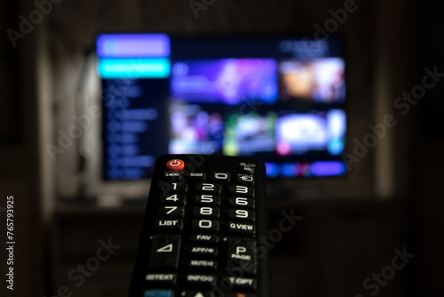 A TV remote control in close-up against the background of a working TV. Watching TV, switching channels
