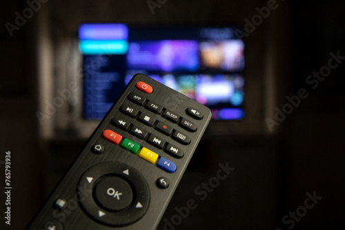 A TV remote control in close-up against the background of a working TV. Watching TV, switching channels