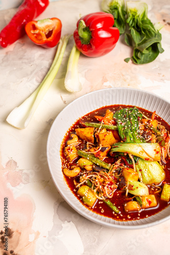 Bowl of red curry with vegetables and tofu on white background