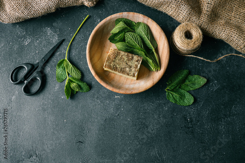 Natural soap with mint in a wooden plate on a dark background