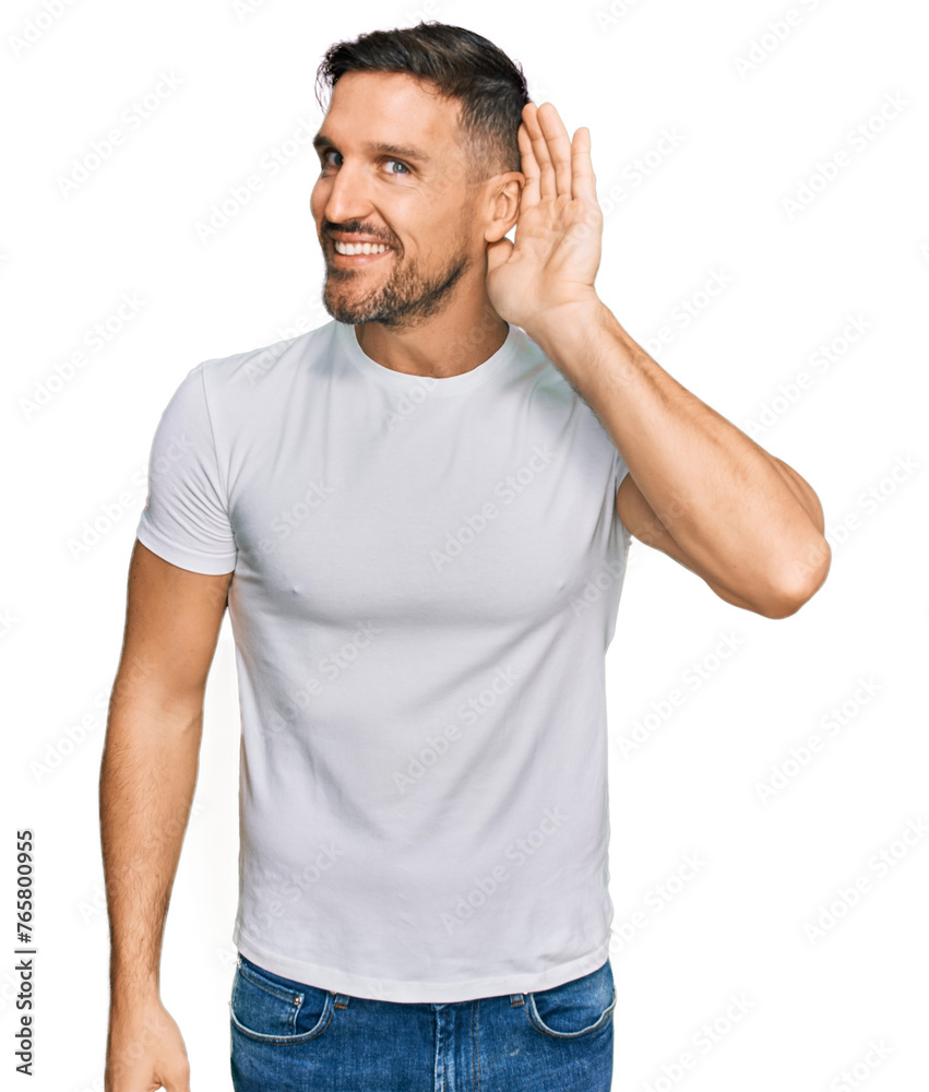 Handsome man with beard wearing casual white t shirt smiling with hand over ear listening an hearing to rumor or gossip. deafness concept. Handsome man with beard wearing casual white t shirt smiling with hand over ear listening an hearing to rumor or gossip. deafness concept.