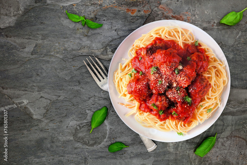 Homemade spaghetti and meatballs with tomato sauce. Above view on a dark stone background.